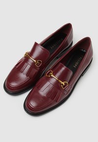 Bordeaux lederen loafers met gouden hardware details en franjes. Ronde neus en platte zwarte zool. Gladde structuur met een gepolijste afwerking.