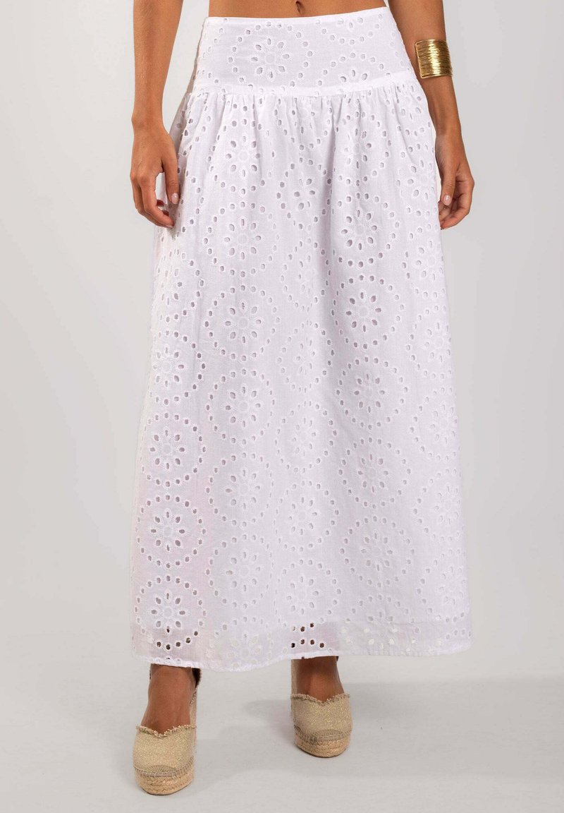 Maxi falda de ojo de perdiz blanca con patrones circulares, cintura fruncida y tela en capas. Llevada con zapatos de esparto color beige.