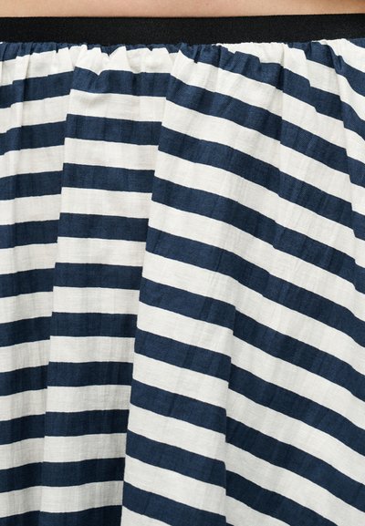 Ύφασμα με οριζόντιες ρίγες σε ναυτικό μπλε και λευκό, μαζεμένο στην κορυφή, δημιουργώντας πτυχώσεις και υφή.