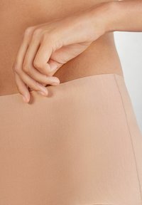 Beige naadloze vormende shorts met een gladde textuur, voorzien van een brede, elastische tailleband en zonder zichtbare naden voor comfort.