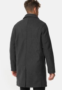 Dark grey wool coat with a notched collar, long sleeves, and a straight cut. Features side pockets and back vent detail.