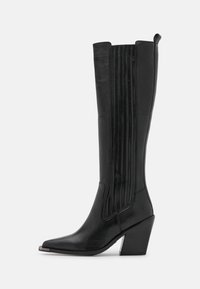 Czarne skórzane botki do kolan z ostrym noskiem, z wzorem w żeberka i masywnym obcasem. Gładka tekstura z błyszczącym wykończeniem.