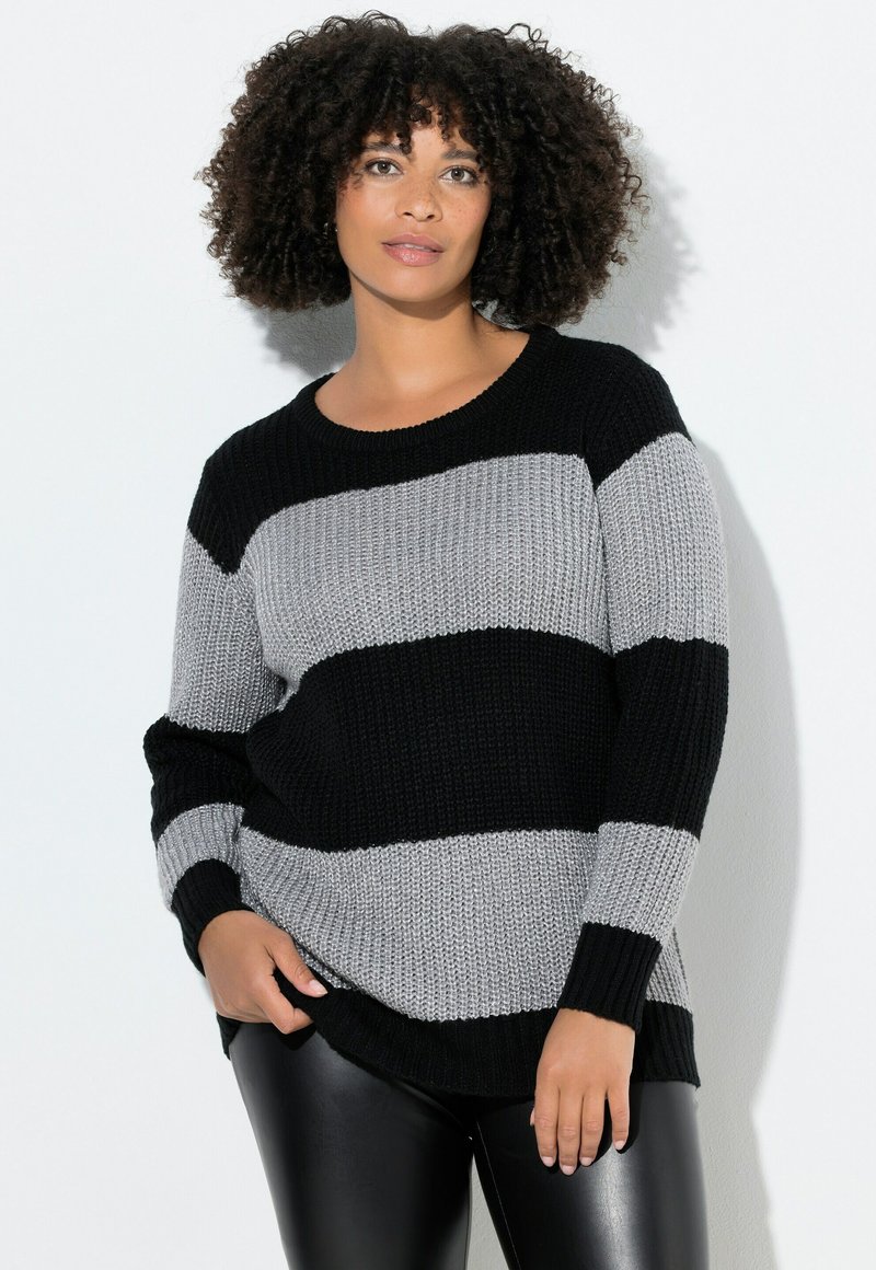 Schwarzer und grauer gestreifter Strickpullover mit lockerer Passform, rundem Halsausschnitt und langen Ärmeln, kombiniert mit schwarzen Kunstlederhosen.