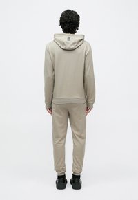 Svetlosivá, mäkká mikina z tkaniny s kapucňou so šnúrkou a rebrovaným lemom, doplnená o zodpovedajúce tepláky. Jednoduchý dizajn bez výrazných vzorov.