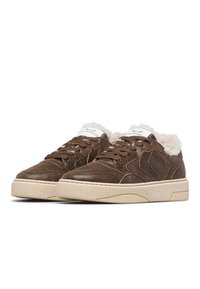 Sneaker in pelle marrone con superficie texture, dettagli color sabbia e fodera in pelliccia bianca. Presentano lacci piatti e suola in gomma beige.
