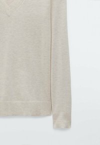 Beige v-neck sweater made of soft fabric, featuring long sleeves and ribbed cuffs and hem, with a smooth texture and minimal design.