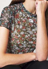 Síťovaný top s květinovým potiskem a krátkými rukávy v zelené, bílé, růžové a červené barvě. Na prsou je umístěna nášivka s logem Nike. Měkká textura.