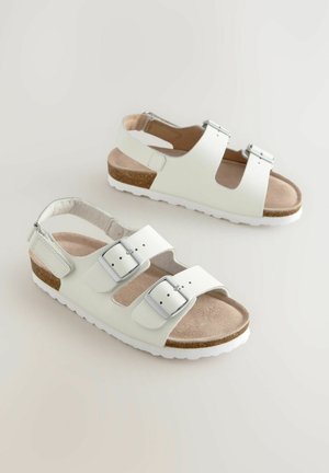 Weiße Sandalen mit drei verstellbaren Schnallen, Korkfußbett und Gummisohle. Offenes Rückendesign mit einer flachen, strukturierten Oberfläche.