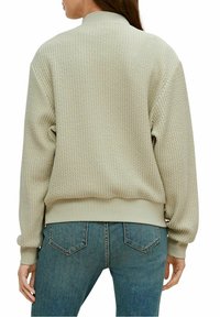 Sweat-shirt vert clair texturé avec un col et des poignets côtelés, présentant une coupe décontractée et un motif tissé subtil.