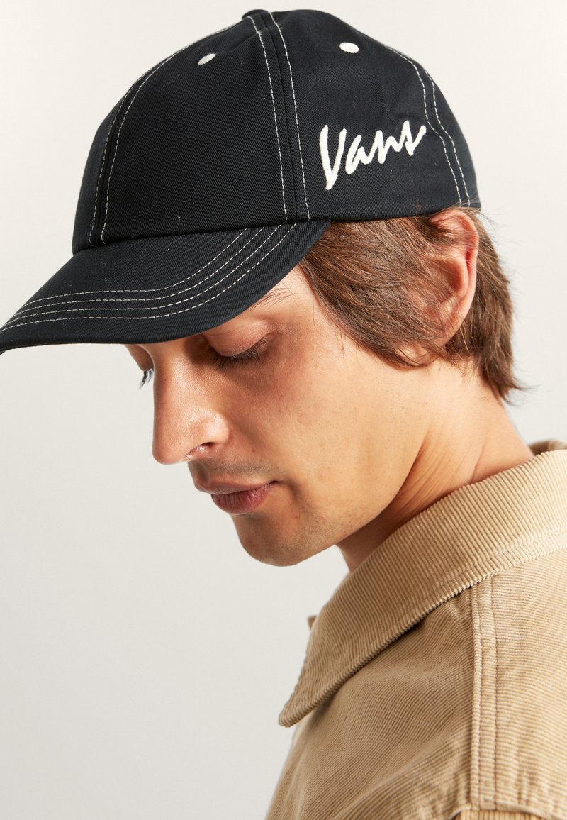 Gorra de béisbol negra con logotipo blanco bordado, con costuras contrastantes, visera curva y seis ojales de ventilación.