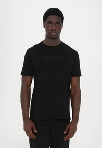 Schwarzes Kurzarm-T-Shirt mit Rundhalsausschnitt, auf der Vorderseite mit einem tonal aufgedruckten "Armani Exchange"-Logo. Weicher Stoff. Einfaches Design.