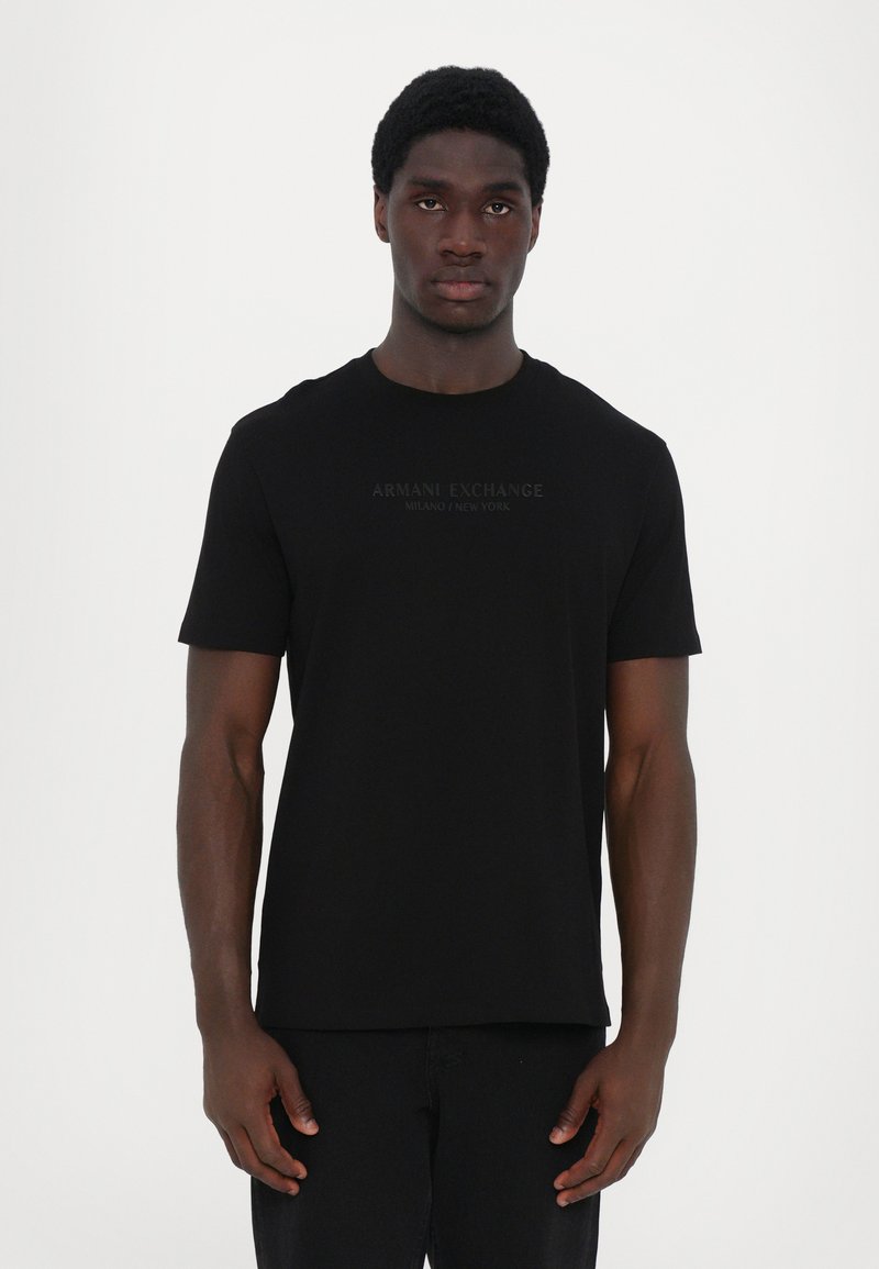 Schwarzes Kurzarm-T-Shirt mit Rundhalsausschnitt, auf der Vorderseite mit einem tonal aufgedruckten "Armani Exchange"-Logo. Weicher Stoff. Einfaches Design.
