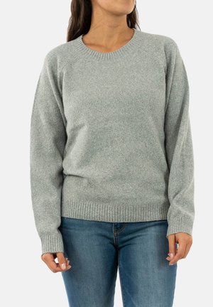 Suéter de punto gris con cuello redondo, mangas raglán y dobladillo acanalado, combinado con jeans azules. Textura suave y diseño casual.