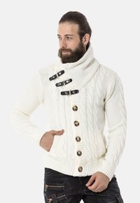 Weißer Strickpullover mit hohem Kragen, vier schwarzen Knöpfen und gerippten Bündchen sowie Saum. Zwei vordere Taschen sichtbar.