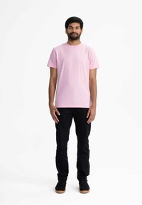 Roze crew-neck t-shirt met korte mouwen, gecombineerd met zwarte broek en zwarte schoenen met rubberen zolen. Eenvoudig ontwerp, effen kleuren, casual pasvorm.