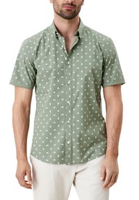 Koszula krótko rękawowa z guzikami w stonowanej zieleni z bawełny, w białe wzory w romby; kołnierzyk oraz prosty dół z luźnym krojem.