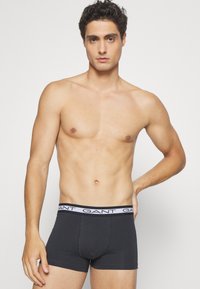 Dark gray boxer briefs with a white waistband featuring the brand name “GANT” in bold. Smooth fabric with a snug fit.