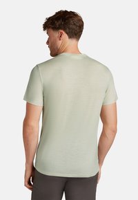 Grünes T-Shirt mit kurzen Ärmeln, glatter Textur und rundem Ausschnitt, das über ein dezentes, weiches Finish verfügt. Minimalistisches Design, keine Grafiken.