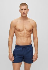 Marineblaue Schwimmshorts mit elastischem Bund und Kordelzug. Glatte Textur, knielang und ohne sichtbare Muster oder Akzente.