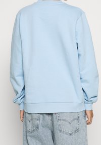 Ljusblå sweatshirt med långa ärmar, ribbade muddar och fåll, tillverkad av mjukt material, med rund halsringning och avslappnad passform.