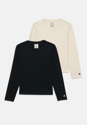 Deux t-shirts à manches longues : un noir et un crème. Les deux sont en coton doux avec un col rond et un logo brodé sur la manche.