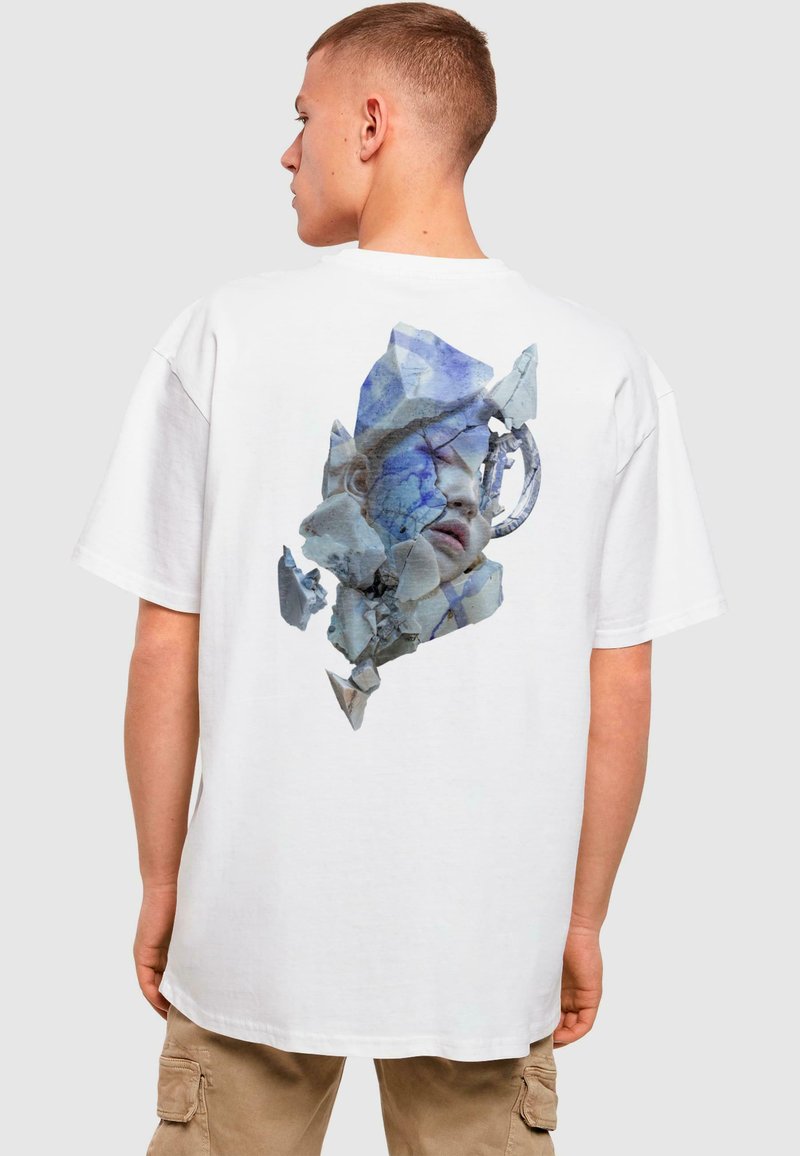 Weißes Baumwoll-T-Shirt mit einem blauen und grauen fragmentierten Gesichtsgrafik auf der Rückseite. Lockerer Schnitt mit kurzen Ärmeln.