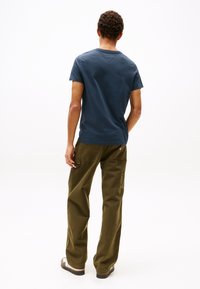 Navy blue short-sleeve t-shirt with a crew neckline, paired with olive green cargo pants featuring multiple pockets and a patch accent.