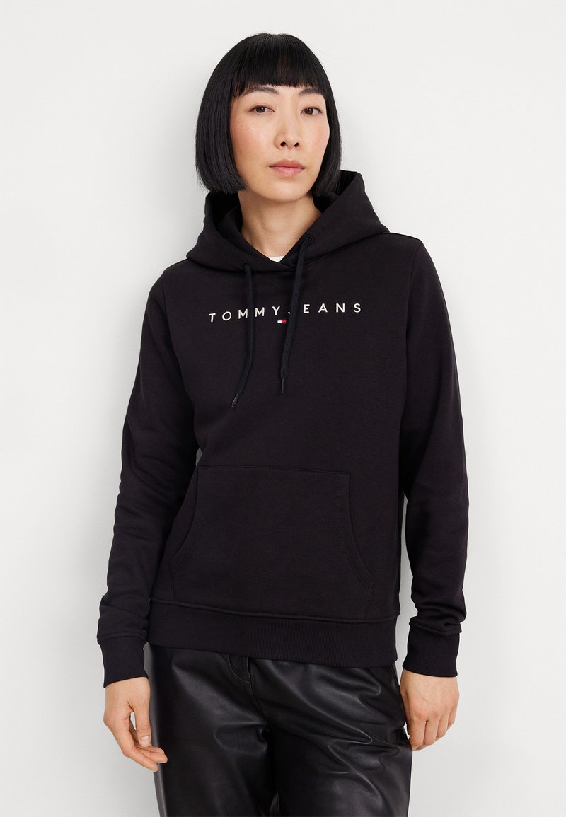 Sudadera negra con cordones, bolsillo frontal y "TOMMY JEANS" impreso en blanco en el pecho. Fabricada con una suave tela texturizada.