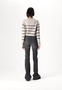Gray striped sweater with black lines, paired with dark gray flared jeans. The outfit features a casual fit and soft texture.