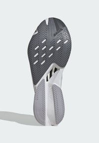 Schuhsohle mit einer grauen Gummiunterseite, die ein strukturiertes Muster für Traktion aufweist, sichtbare Rillen und eine weiße Zwischensohle mit der Aufschrift "ADIZERO".