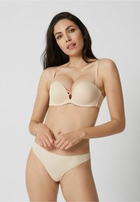 Beige molded cup bra with adjustable straps and a keyhole detail. Paired with matching beige bikini panties, smooth fabric texture.