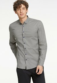 Camisa gris de botones con un patrón geométrico en azul oscuro. Tiene cuello, mangas largas y botones azules para el cierre.