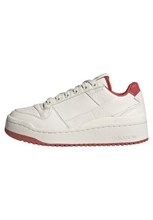 Witte lage sneaker met rode accenten, dikke zool en vetersluiting, gezien van de zijkant op een witte achtergrond.