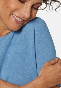 Hellblauer Strickpullover mit weicher Textur, runder Ausschnitt und dezenten Nähten an den Ärmeln.