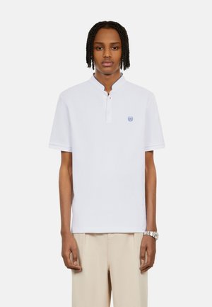 Vit kortärmad polo med krage, utsmyckad med en blå broderad logotyp på bröstet och en smidig bomullstextur.