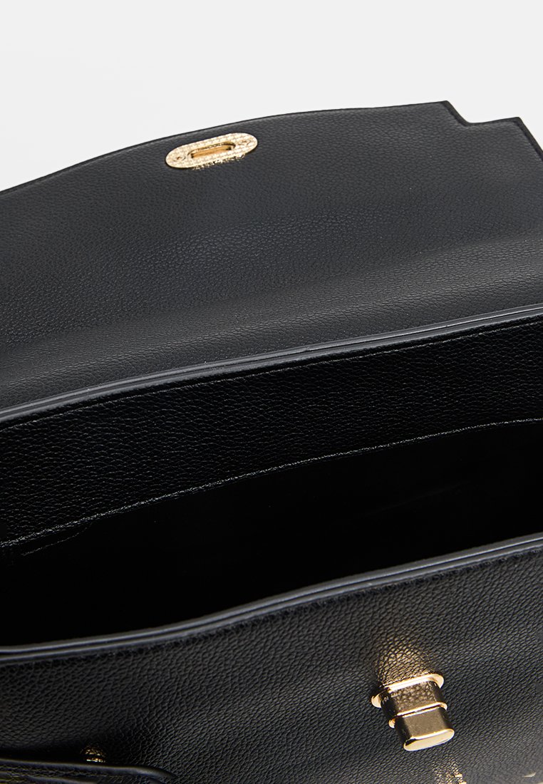 Sac à main en cuir noir avec une finition texturée, quincaillerie dorée et fermeture magnétique. L'intérieur est doublé d'un tissu doux.