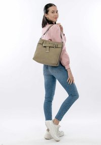 Light khaki crossbody bag with a rectangular shape, featuring a buckle accent and short handle; smooth texture with subtle detailing.