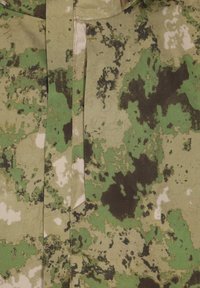 Camouflage stof met verschillende tinten groen, zwart en crème, met een gestructureerd oppervlak, dat een gevlekte patroon en subtiele imperfecties vertoont.