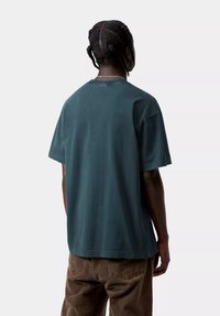 T-shirt en coton surdimensionné de couleur bleu sarcelle foncé avec un col rond et des manches courtes, présentant une texture lisse et une coupe décontractée.