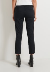 Pantalons noirs sur mesure avec une coupe slim, longueur raccourcie et une texture lisse. Présente deux poches arrière et un détail subtil à la ceinture.
