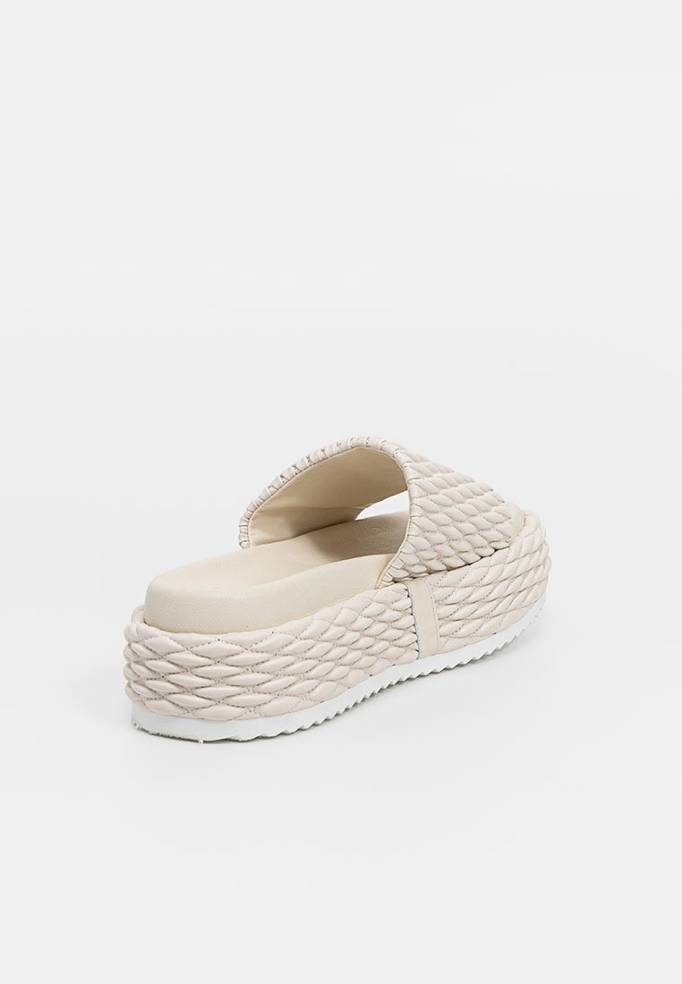 Beżowe klapki na platformie z plecioną, teksturowaną górą i podeszwą, wyposażone w wyściełane wnętrze oraz białą, żłobioną podeszwę.