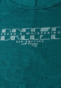 T-shirt en tissu turquoise avec le texte "FRESH & WHISPERING BREEZE SUN TOUCHED and happy" en blanc, avec une finition texturée.