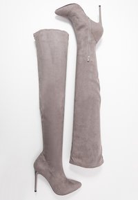Botas de ante gris por encima de la rodilla con puntera punta y alto tacón de aguja, que cuentan con un cierre lateral y una textura suave.