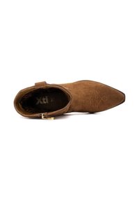 Botín de ante marrón con punta afilada y cremallera lateral, que presenta un diseño grabado en el empaque y un forro interior de estampado de leopardo.