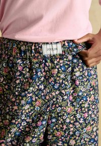 Kvetinové nohavice s námorníckym pozadím, obsahujúce odtiene ružovej a zelenej. Elastický pás so značkou "JOULES". Mäkká textúra látky.