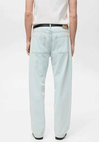 Lichtblauwe denim jeans met een rechte snit, voorzien van twee achterzakken en een leren patch boven de tailleband, gecombineerd met een zwarte riem.