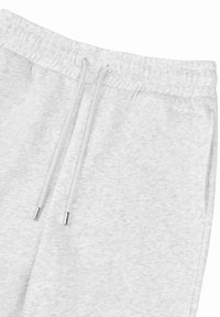 Grå joggebukser med elastisk midjebånd, snor og metalliske ender. Mykt stoff med melert tekstur, minimal merkevare på siden.