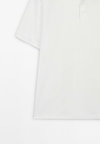 Bílá polo košile s krátkým rukávem, která má tříknoflíkovou légu, hladký materiál a volný střih. Čistý design bez vzorů.