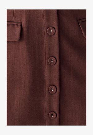 Bordo srajca iz gladkega, teksturiranega blaga z gumbom spredaj. Dva žepa na prsih in šest okroglih gumbov z rahlim leskom.