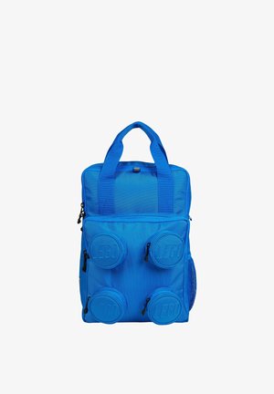 Sac à dos bleu avec quatre compartiments ronds en relief portant le logo LEGO à l'avant et deux petites poignées en haut sur fond blanc.